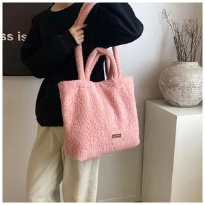 Close-up of pink fluffy plush tote bag with a small brand tag worn on a model's shoulder