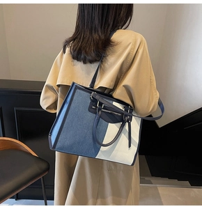 Detailed view of large color-block tote bag with zip pocket and tassel on a model