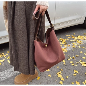 Détail d'un sac cabas en daim rouge avec fermoir doré sur un fond d'automne chaud