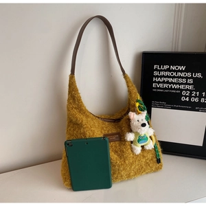 Detail of plush yellow tote bag with brown leather strap and a cute dog plush keychain