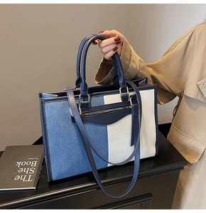 Detail of denim and leather tote bag with gold D-rings and front zipper accent