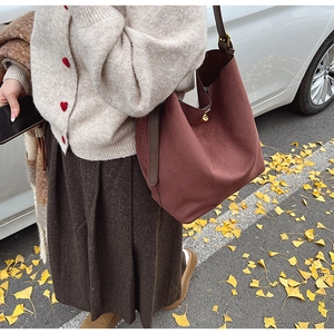 Détail macro du sac cabas bordeaux en daim avec anses en cuir et boucle en métal