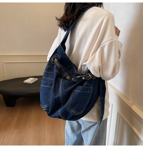 Detail of blue denim tote bag with multiple pockets and leather straps for women