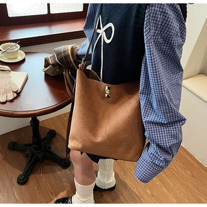 Sac seau en daim marron avec fermoir rotatif en métal dans un café chaleureux