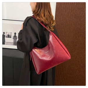 Deep red leather tote bag showing large capacity and fashion text on model's shoulder