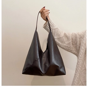 Detail view of the asymmetric coffee brown tote bag with textured synthetic leather finish