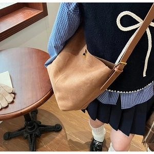 Détail d'un sac cabas en daim marron avec fermoir doré et bandoulière en cuir réglable