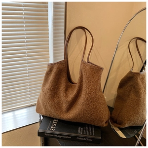 Brown fuzzy faux shearling tote bag with leather handles in a minimalist aesthetic