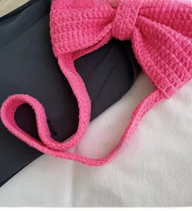 Vue détaillée du sac rose tricoté à la main avec nœud et longue bandoulière souple