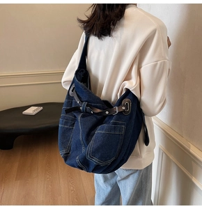 Detail of large denim shoulder bag with brown leather buckle and contrast stitching