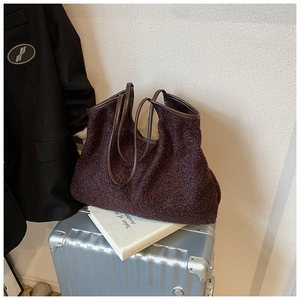 Fashionable dark brown fleece tote bag with leather handles on a silver suitcase