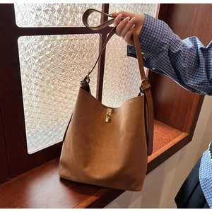 Détail d'un sac cabas en daim marron avec boucle en métal doré et bandoulière en cuir