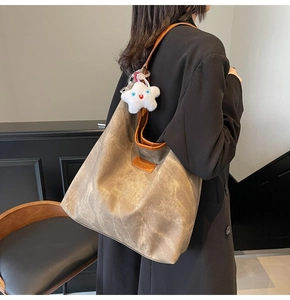 Detail of taupe canvas tote with leather trim and plush star charm on a model
