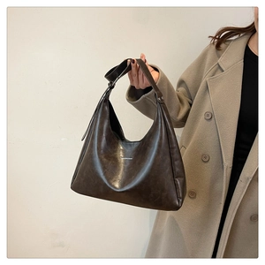 Detail view of brown faux leather crescent bag with adjustable strap and vintage texture