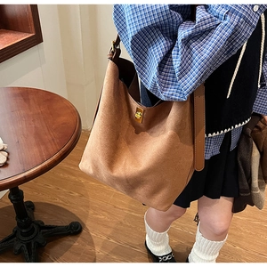 Gros plan du fermoir doré et de la texture en daim sur un grand sac cabas marron