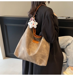 Detail of tan canvas tote bag featuring an orange logo patch and white plush star charm
