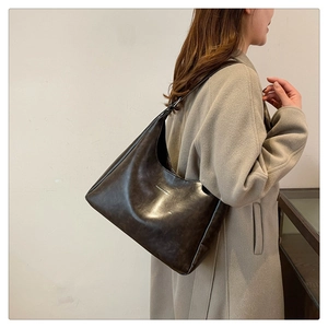 Detailed view of dark brown faux leather texture and golden logo on hobo shoulder bag