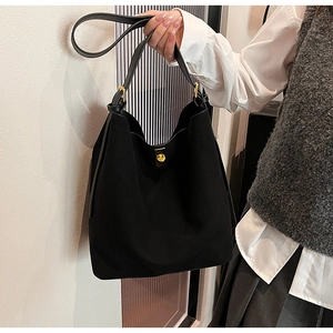 Détail du grand sac cabas en daim noir avec fermoir tournant doré et bandoulière