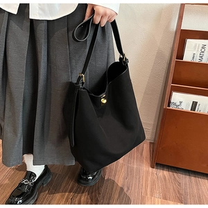 Détail du sac cabas en daim noir avec fermoir tournant doré et bandoulière élégante