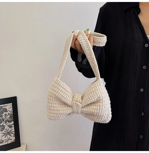 Détail du sac à bandoulière en crochet fait main avec un grand nœud crème et texture tricot