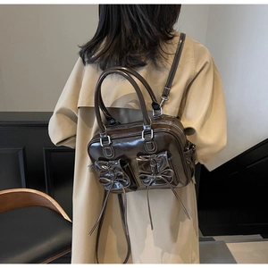 Detail of dark brown glossy leather backpack with twin bow pockets in retro vintage style