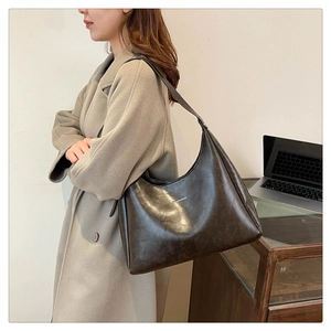 Detail of coffee brown PU leather shoulder bag with glossy finish and silver logo