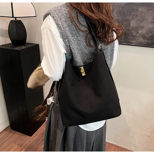 Détail du sac seau noir en daim avec boucle dorée et intérieur spacieux pour le travail