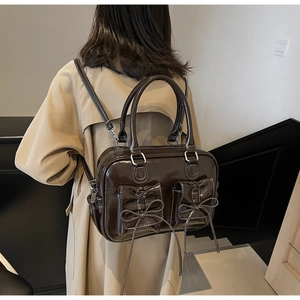 Detail of dark brown patent leather backpack with white stitching and bow pockets