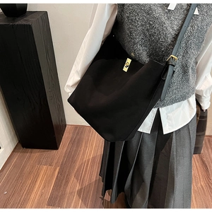 Détail du sac cabas en similicuir noir avec bandoulière réglable et fermoir doré rotatif
