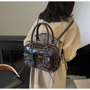 Detail of vintage dark brown glossy backpack with bow pockets on beige trench coat