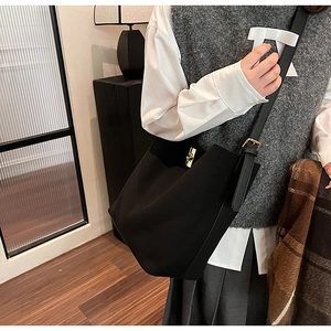 Détail du sac seau noir en daim avec un fermoir rotatif en métal doré poli élégant