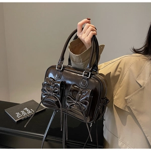 Detail of vintage chocolate brown glossy handbag with bow pockets and silver metal hardware