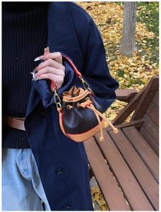Détail du sac seau avec bords rouges et logo doré sur le fond du sac mini