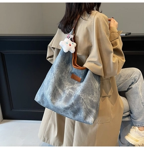 Detail of grey-blue canvas tote with brown leather handles and plush star charm