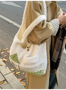 Détail du sac cabas en peluche blanche avec écussons à carreaux verts et dentelle