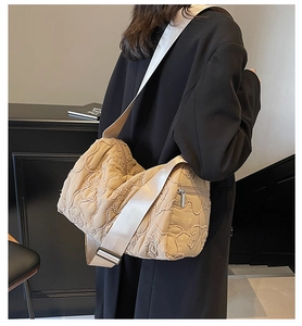 Model wearing a beige quilted floral crossbody bag with a wide woven shoulder strap