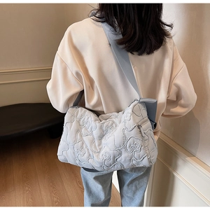 Detail of light blue quilted bubble crossbody bag with floral texture and wide strap