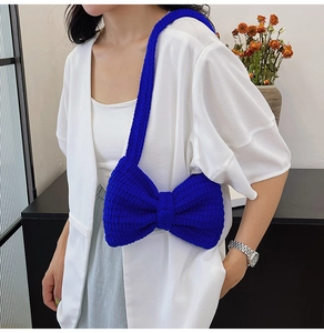 Détail d'un sac à bandoulière en tricot bleu avec un grand nœud fait à la main