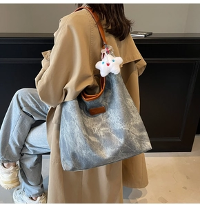 Close-up of stylish large canvas tote bag with leather straps and plush star pendant