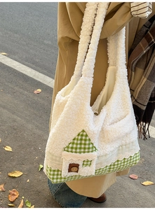 Détail d'un sac cabas en peluche blanche avec motif maison à carreaux verts et dentelle