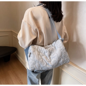 Detail of light blue quilted fabric shoulder bag shown on model in soft lighting
