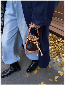 Détail d'un mini sac seau en cuir avec fermeture à cordon et crochet en métal doré