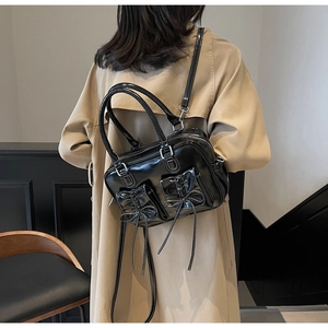 Detail of vintage black shiny handbag with white contrast stitching and bow front pockets