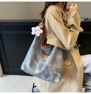 Detail of grey washed canvas tote bag with brown leather trim and star plush charm