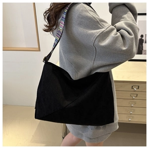 Détail d'un sac en velours côtelé noir avec une bandoulière tissée de style ethnique