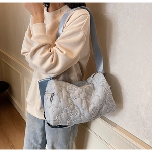 Detail of light blue quilted crossbody bag with flower patterns and fabric shoulder strap