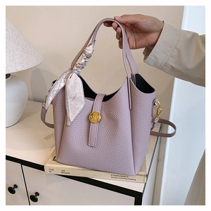 Detail of lilac bucket bag with lychee texture, silk scarf decor and golden N-lock