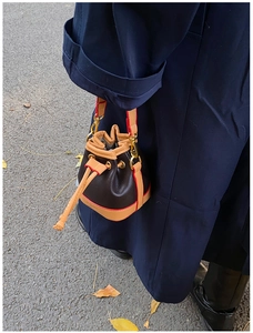 Détail d'un mini sac seau en cuir grainé avec bandoulière et cordons de serrage chic