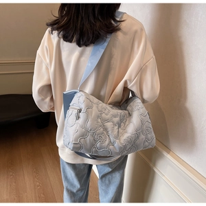 Back view of model wearing a light blue quilted crossbody bag with floral patterns