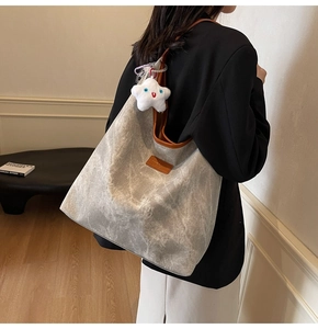 Detail of grey washed canvas tote bag with brown leather trim and white star plush charm